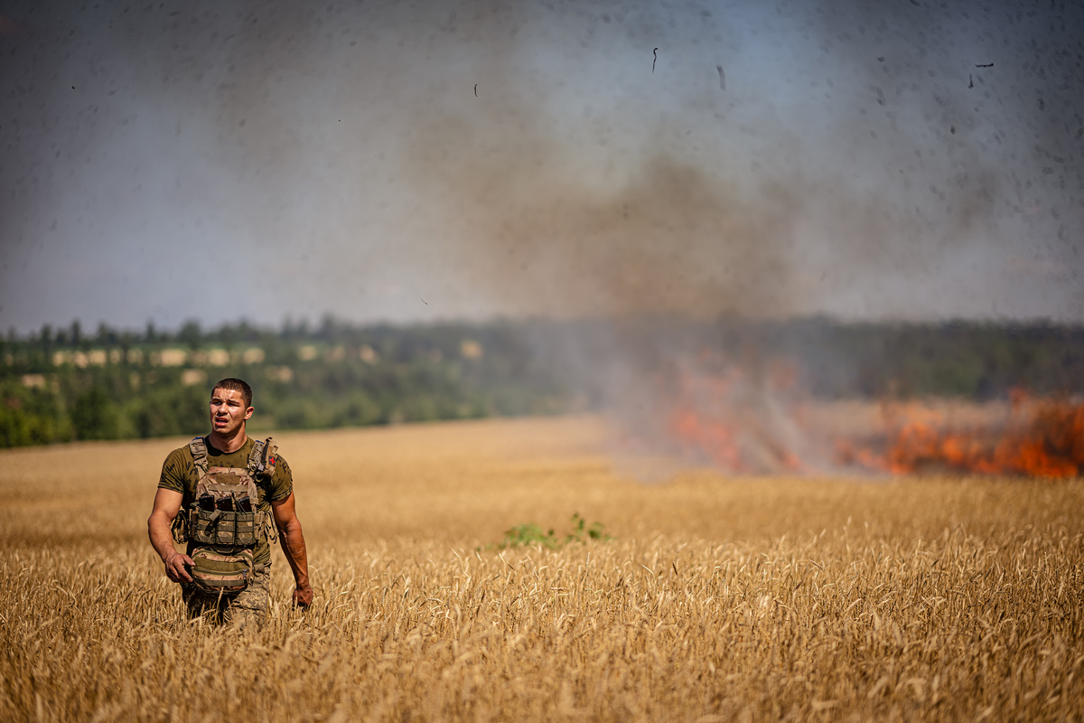 Боєць розрахунку САУ M109 Paladin 23 ОМБр на полі, яке підпалив ворог під час обстрілу. Напрямок Очеретине. Липень 2024.