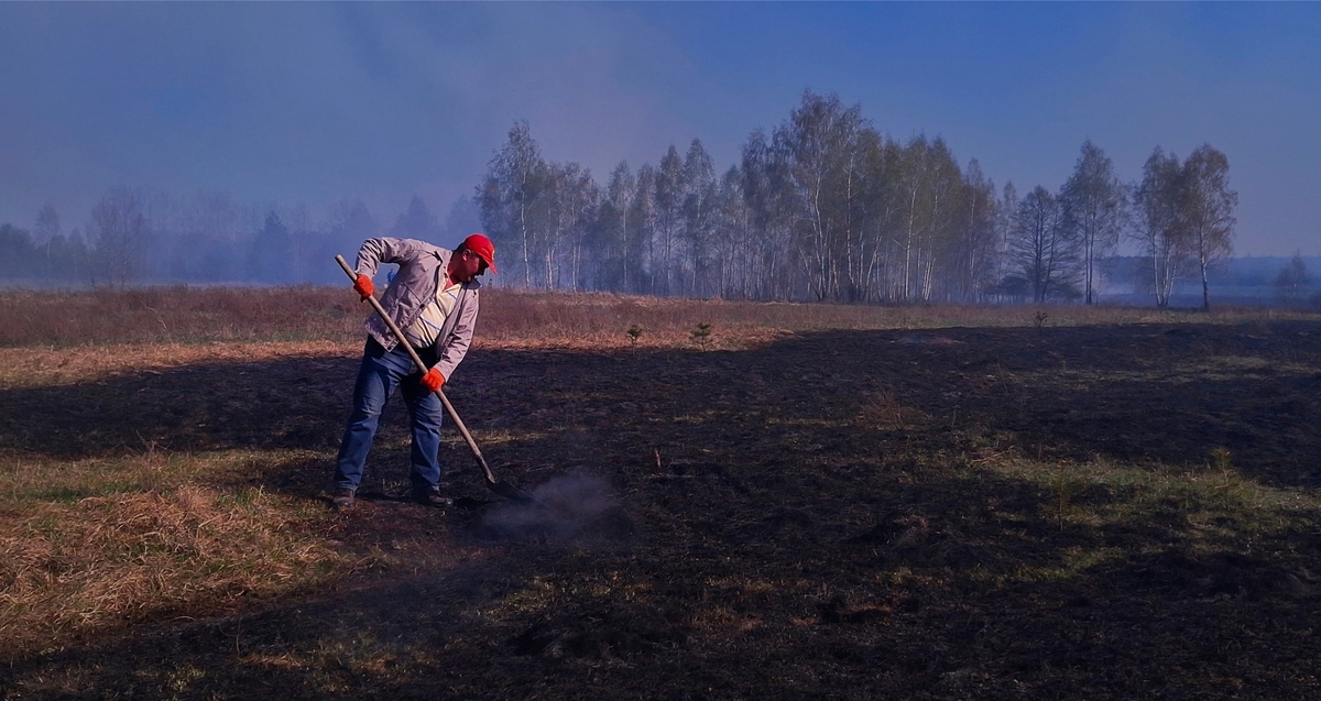 Дата створення: 20.05.2025 Місце: село Соснівка. Країна: Україна. Тема: Вогняний Великдень. Опис: На фото зображений житель села, що тушить залишки вогню землею за допомогою лопати.