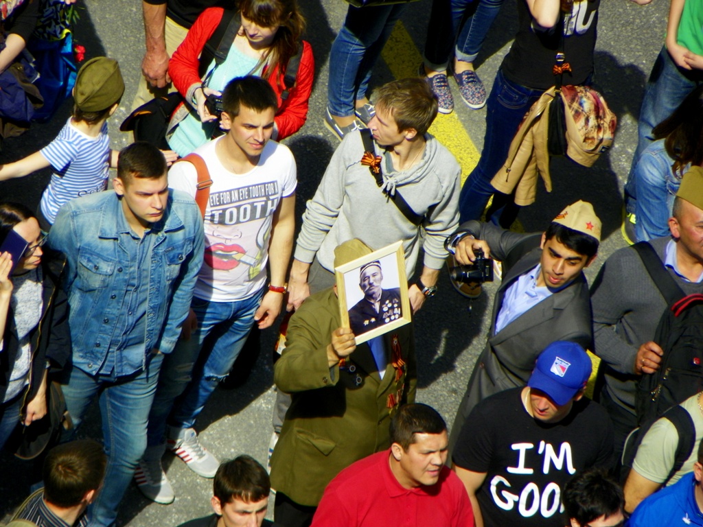 Ветеран с портретом, окруженный молодыми людьми